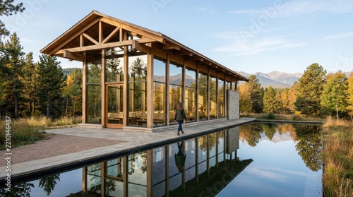 Modern wooden pavilion with glass walls reflecting in calm water surrounded by trees