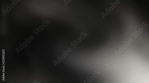 Black matte textured background with floating dust particles illuminated by soft light in the top right corner, creating a deep contrast between black and white. This abstract design emphasizes textur