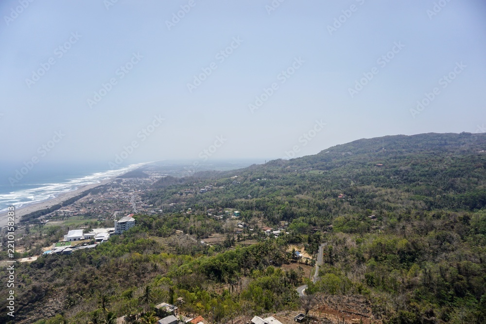Obraz premium A panoramic view of Java's southern coast and the crashing waves of Parangtritis Beach, captured from the top of the Obelix cliff.