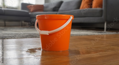 Orange Bucket Spilled Water on Wooden Floor in Living Room Interior