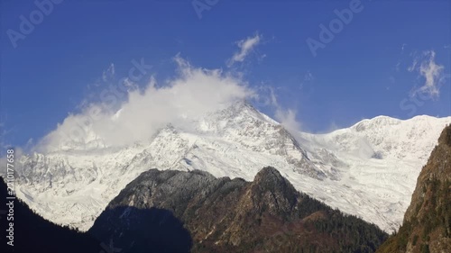 Snowy Mountain Peaks Under a Clear Blue Sky with Clouds