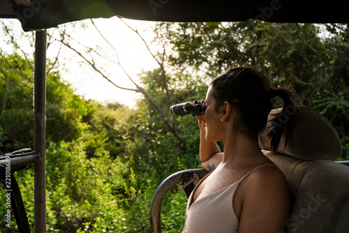 Woman on jungle safari observing nature with binoculars in Sri Lanka