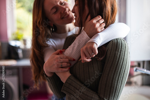 Lesbian couple cuddling affectionately at home in the morning