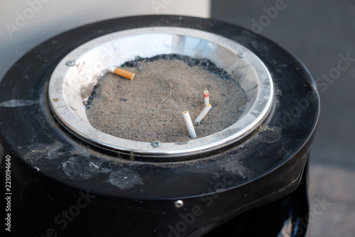 Smoky ash rests in a metal ashtray