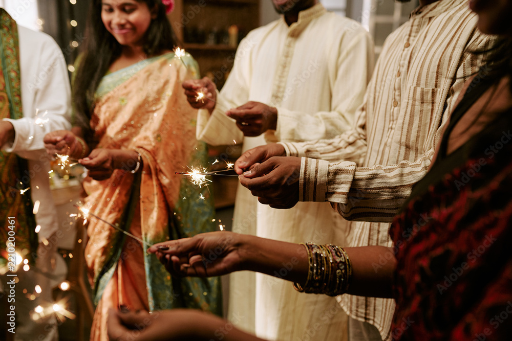 Fototapeta premium Diverse group of young adult Indian friends celebrating cultural festival holding sparklers together. Image useful for holiday marketing campaigns and social diversity media