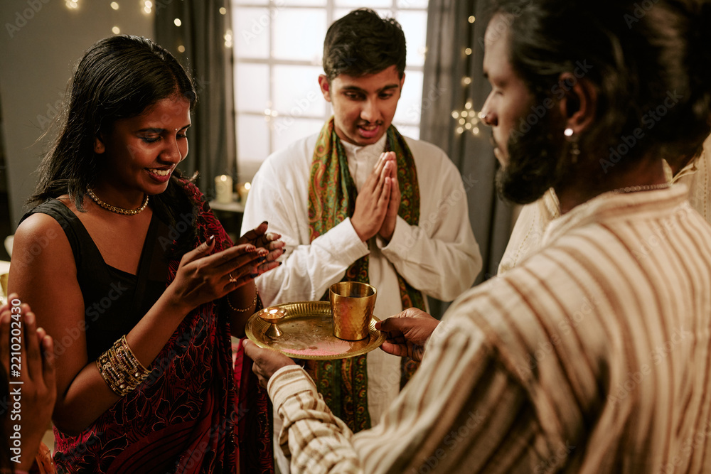 Obraz premium Indian young adults and teenager praying during religious ritual at home celebrating festival of lights. Concept of cultural tradition suitable for holiday advertising campaigns