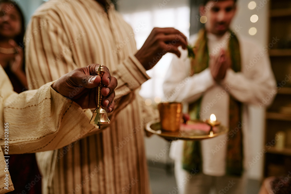 Obraz premium Indian family celebrating festival with prayer ritual holding brass bell and oil lamp tray. Suitable for cultural event marketing, holiday advertising, and religious celebration content