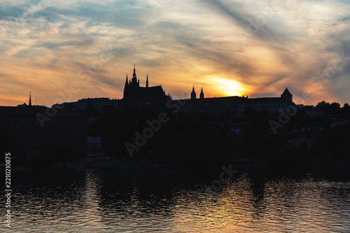 Prague Castle and Saint Vitus Cathedral silhouette at golden sunset over the Vltava river, Czech Republic