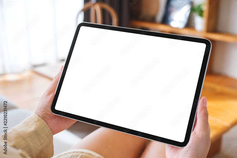 Fototapeta premium Mockup image of a woman holding tablet with blank desktop white screen at home