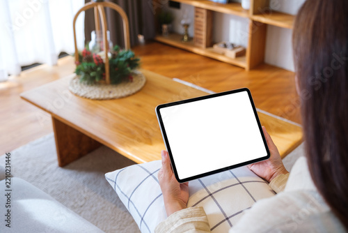 Mockup image of a woman holding tablet with blank desktop white screen at home