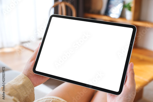 Mockup image of a woman holding tablet with blank desktop white screen at home