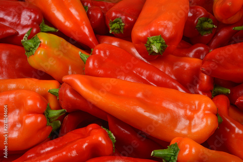 Fotografie A full frame background texture of fresh and vibrant red pointed peppers piled together