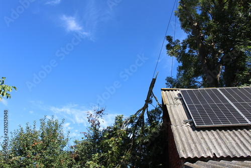 Tree removal service protecting green energy roof infrastructure during hazardous cutting.