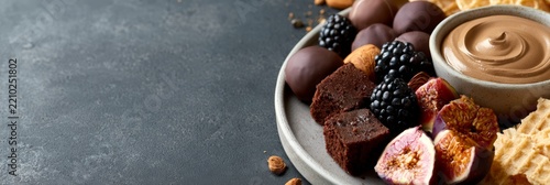 Dark moody dessert plate banner with brownies figs blackberries and chocolate mousse for evening food background and menu layout
