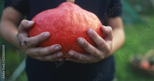 Young boy holding organic pumpkin during fall season at house garden - Healthy food, teenager lifestyle and autumn concept - UGC content