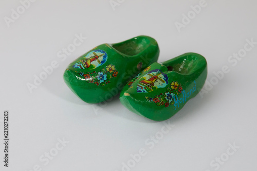 A pair of traditional green souvenir Dutch wooden clogs painted with a windmill, flowers, and the word Holland, isolated on a white background.