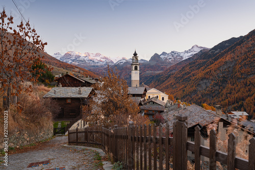 Scenic mountain road leading to the alpine village of Ayas surrounded by golden autumn foliage in Aosta Valley, Italy