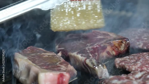 Basting raw ribeye steak with a red silicone brush over a hot grill meat barbecue baste sauce food meat barbecue baste sauce food