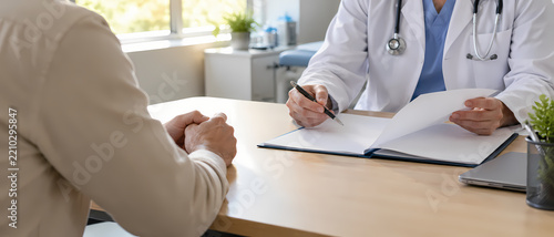 Doctor reviews medical documents with a patient during a healthcare consultation, discussing clinical information and treatment options while explaining records and personalized care planning