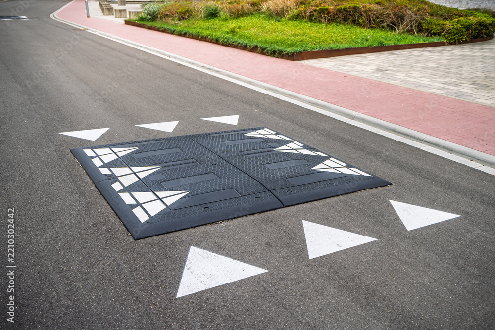 Obraz premium A black rubber speed cushion installed on a quiet suburban asphalt road for traffic calming safety