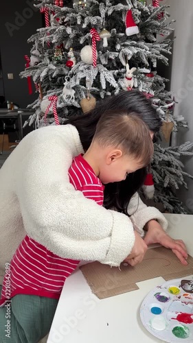 Mother guiding her toddler son while painting