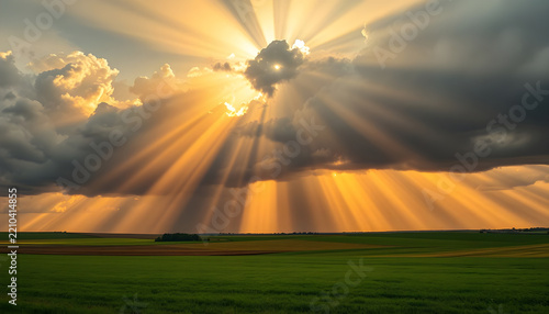 Sunbeams breaking through storm clouds over farmland