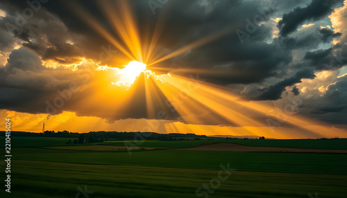 Sunbeams breaking through storm clouds over farmland