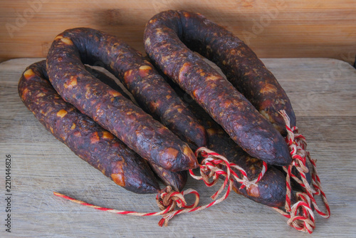 homemade cured sausages or chorizo tied  on a rustic wooden background 