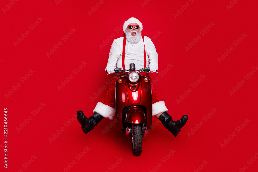 Obraz premium Santa Claus on a red scooter with sunglasses celebrating Christmas in a playful holiday portrait
