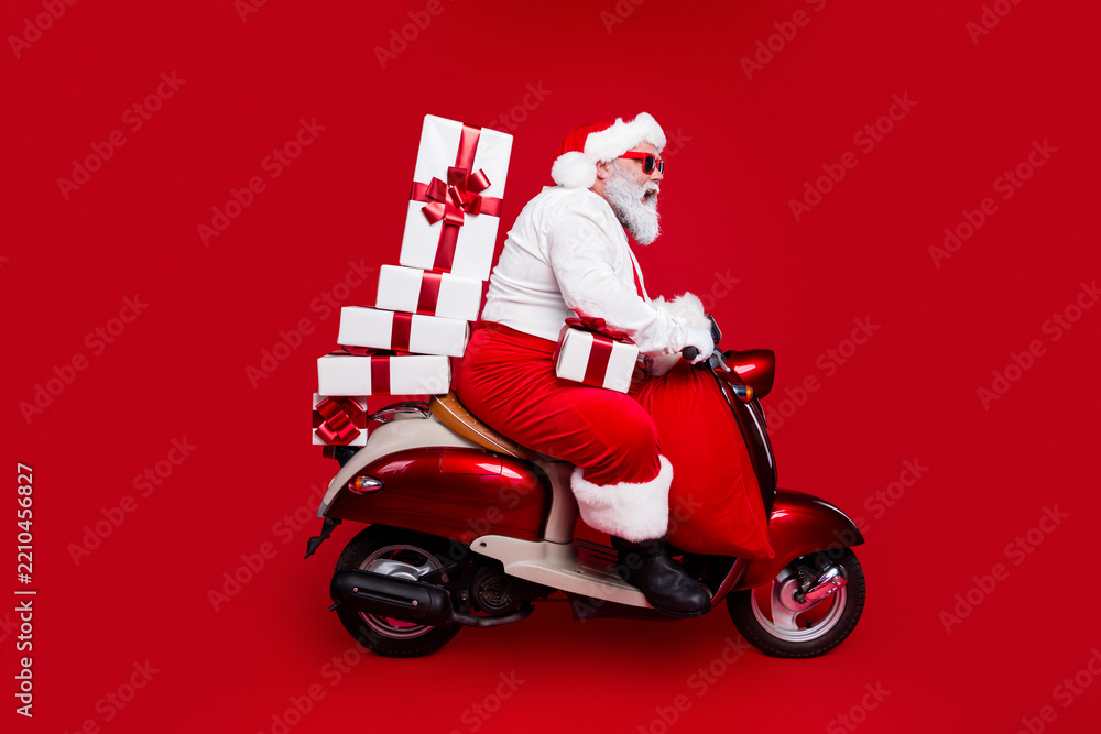 Obraz premium Santa Claus on a red scooter delivering Christmas gifts with festive sunglasses and a sack of presents, modern holiday delivery scene conveying joy, fun, celebration and festive spirit