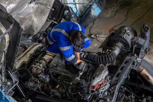 Caucasian mechanic is inspecting the diesel truck engine after annual check up in the professional garage and maintenance all the filter and gear for safety driving concept
