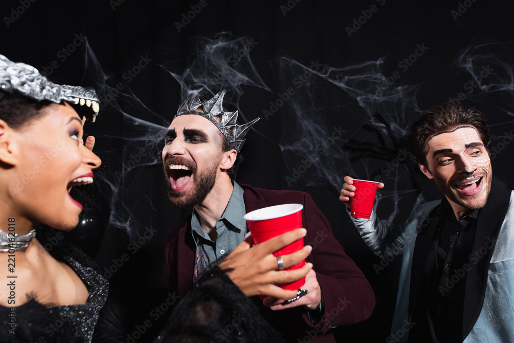 Obraz premium Cheerful multicultural friends celebrating Halloween at a lively costume party