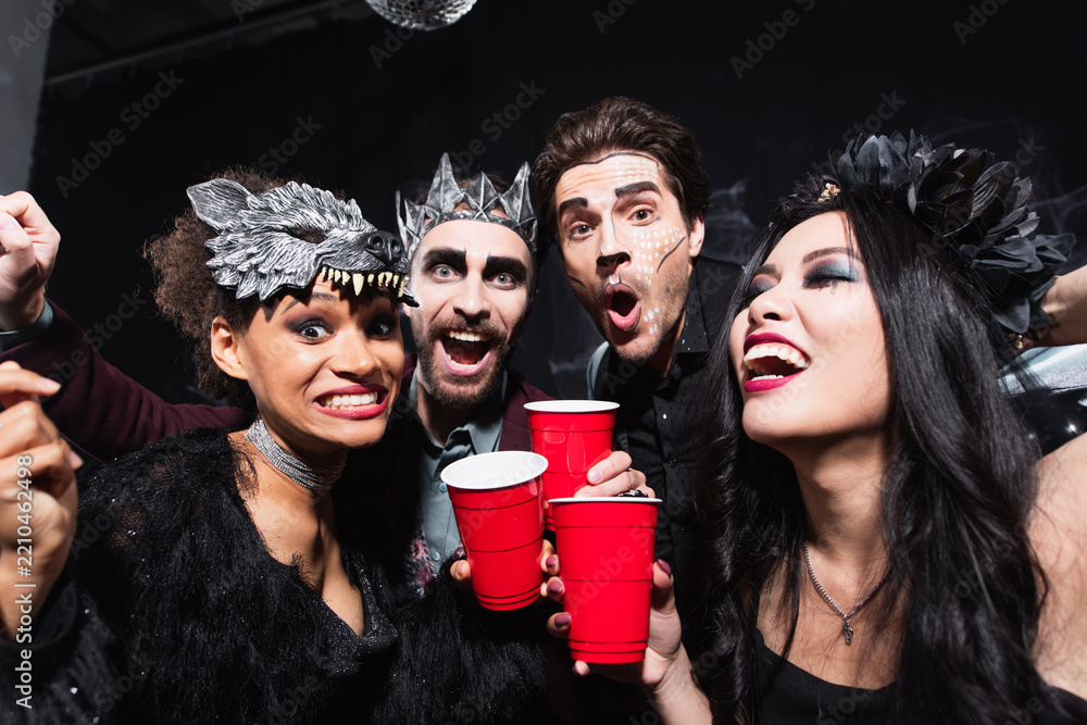 Obraz premium Multicultural friends celebrate Halloween with creative costumes and drinks