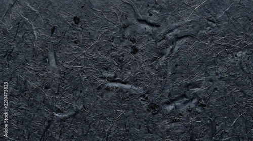 Close-up of textured black asphalt surface highlighting cracks and unevenness for urban design and abstract background