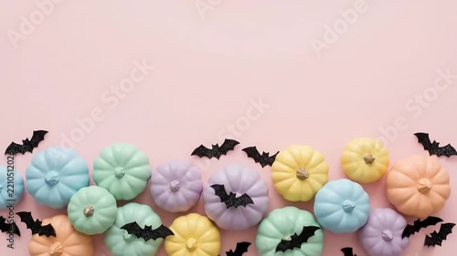 Pastel pumpkins and black bats arranged on pink background for holiday celebration