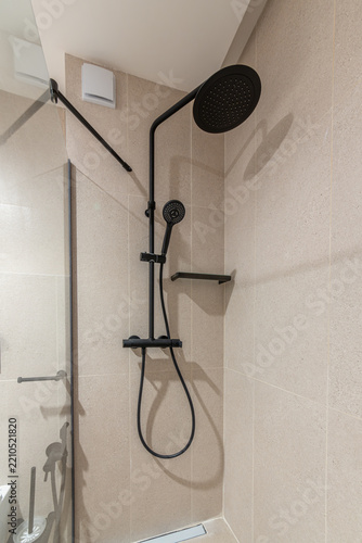 Stylish modern shower with black matte fixtures, a rainfall shower head, and gray tile. Elegant bathroom interior design for a contemporary home or hotel.
