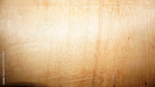 Light plywood surface with soft grain lines and warm golden glow.