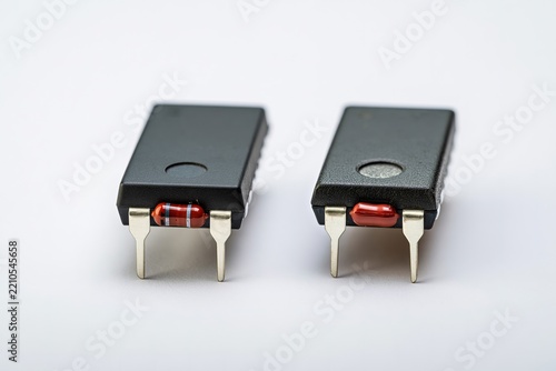 Two Black Rectangular Devices with Red Capsules and Metal Pins