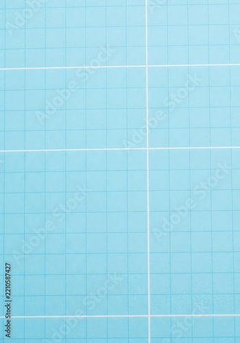A high resolution macro view of a light blue notebook page featuring a clean white grid line pattern with subtle paper fiber textures, blue, supply, professional