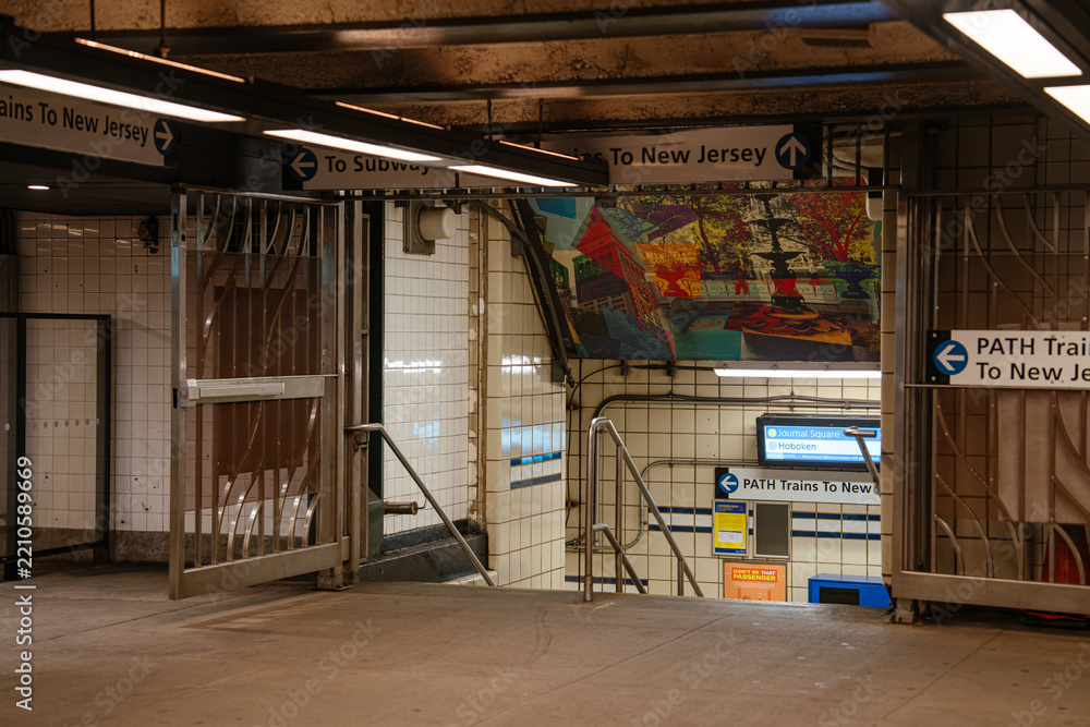 Fototapeta premium New York City, New York, USA - 08.05.2024: Interior corridor of a subway station with directional signs pointing to PATH trains to New Jersey. Underground transportation passage connects commuters