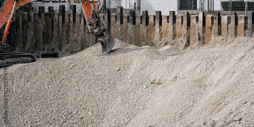 Excavator digging a foundation pit at an urban construction site, heavy machiner