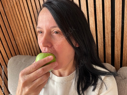 Woman biting fresh green apple, healthy snack and balanced nutrition concept