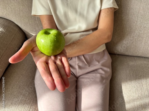 Close up of woman holding fresh green apple in hand, healthy food and diet concept