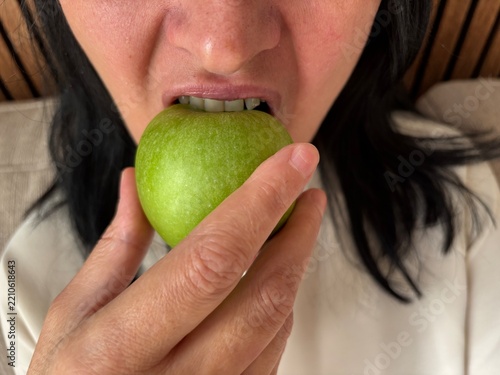Woman biting fresh green apple, healthy snack and balanced nutrition concept