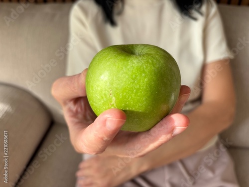Close up of woman holding fresh green apple in hand, healthy food and diet concept