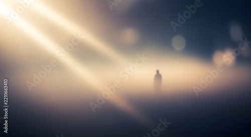 Obraz na plátně Lone silhouette figure standing in deep fog with cinematic sun rays and bokeh li