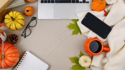 Cozy autumn workspace flat lay with laptop, smartphone, coffee, notebook, pumpkins and large copy space.