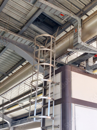 Industrial steel fixed ladder with safety cage leading to building roof access