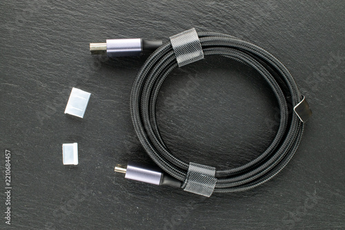 High-speed HDMI cable with nylon braiding and protective caps on slate stone, macro shot.