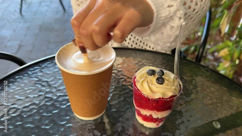 Hand Stirring Foamy Drink Beside Layered Berry Dessert
